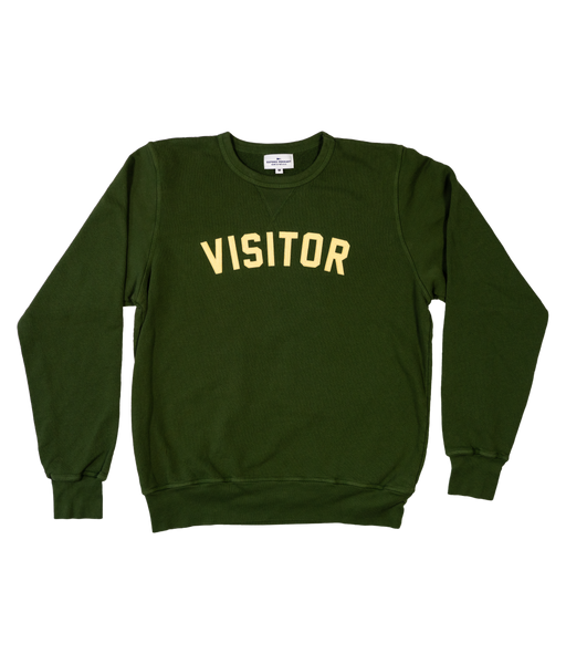 Green medium crewneck sweater. Curved lettering stitched that reads "VISITOR".