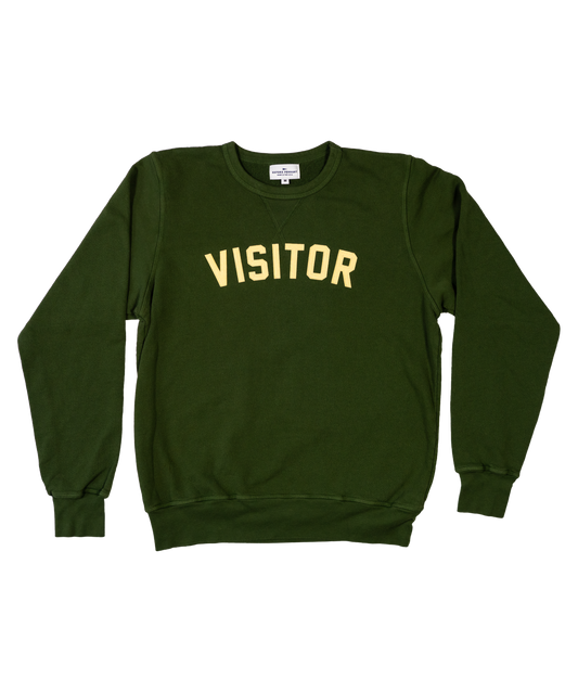 Green medium crewneck sweater. Curved lettering stitched that reads "VISITOR".