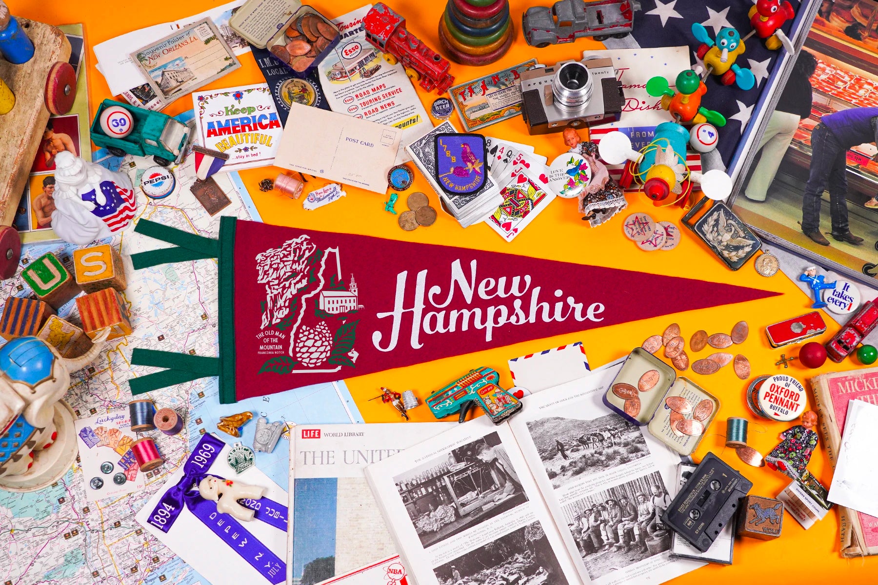 Collection of New Hampshire-themed items including a flag, photos, and souvenirs on a yellow background.